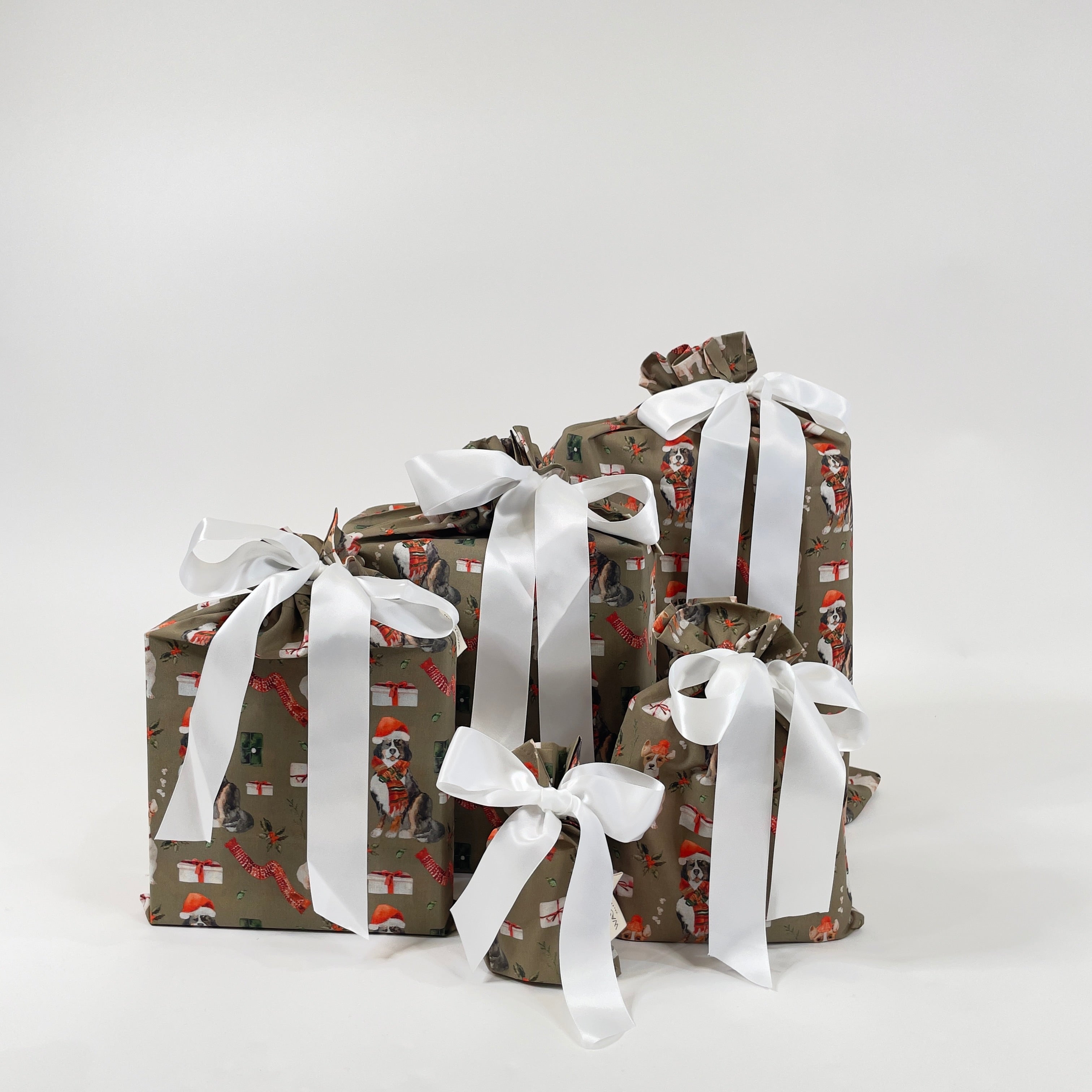 Set of 5 reusable gift bags in a design of dogs and gifts, with a large white bow.